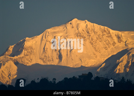 Peaks of the Kangchenjunga mountain range, Sikkim, at dawn. Pemayangtse monastery can be seen on the hilltop in the foreground. Stock Photo