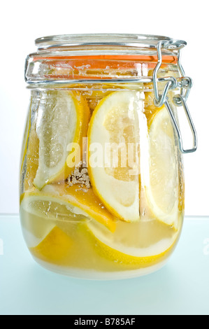 Parfait jar of preserved lemons. Quarters of lemons are covered in salt then topped up with lemon juice. Used in Moroccan food. Stock Photo