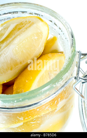 Parfait jar of preserved lemons. Quarters of lemons are covered in salt then topped up with lemon juice. Used in Moroccan food. Stock Photo