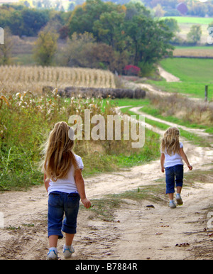 Twin four year old girls take a walk on a country road Stock Photo