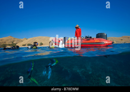 Divers ardously clamber on to the boat after diving, Indonesia, South Asia Stock Photo