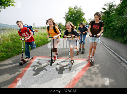 School children, boys and girls, riding kick scooters, push scooters on the way from school, Basel, Switzerland, Europe Stock Photo