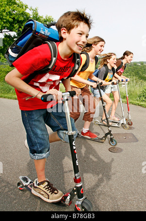 School children, boys and girls, riding kick scooters, push scooters on the way from school, Basel, Switzerland, Europe Stock Photo