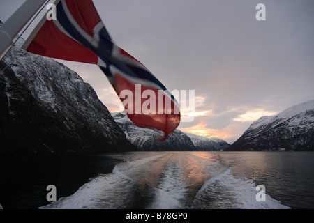 Rock, Norwegian flag and the wake behind a ship in the Geirangerfjord, Norway, Scandinavia, Europe Stock Photo