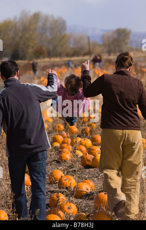 Parents swinging their daughter in a pumpkin patch in Fallon Nevada Stock Photo