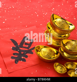 Close-up of gold ingots, red envelopes and Chinese script Stock Photo