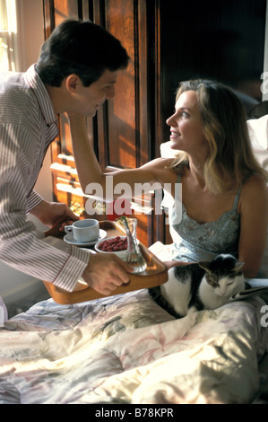 Man bringing woman breakfast in bed. Stock Photo