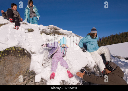 Four children sliding off a snowy rock at Sierra at Tahoe ski resort near Lake Tahoe in California Stock Photo