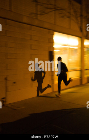 A man running along the road at night under the lights of Reno in Nevada Stock Photo