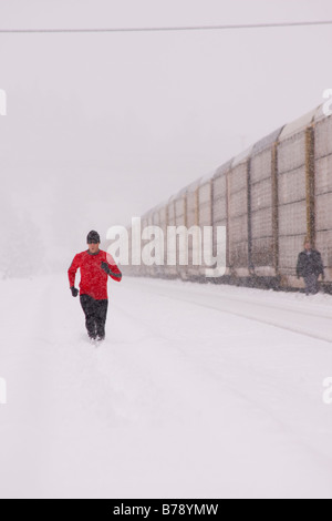 A man running next to a train on a snowy day near Truckee in California Stock Photo