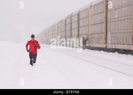 A man running next to a train on a snowy day near Truckee in California Stock Photo
