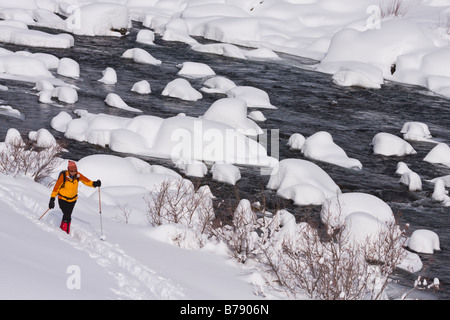 A woman skiing along the Truckee River on a snowy day in California Stock Photo