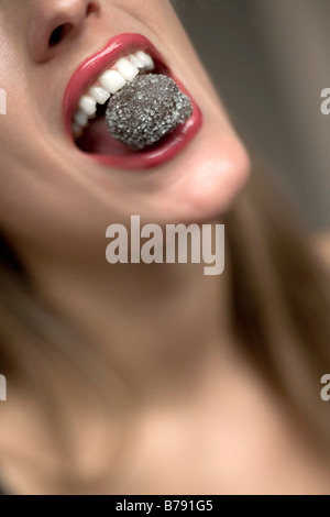 Young woman eating chocolate praline, portrait Stock Photo