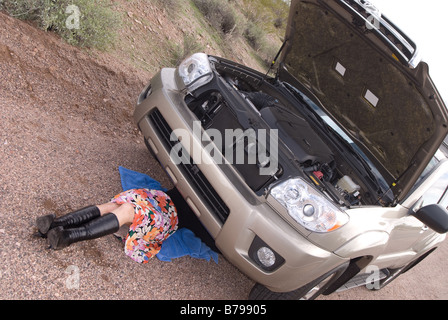 A woman deals with her broken car on a remote dirt road Stock Photo