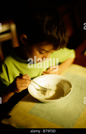 Six year old boy eating porridge at breakfast Stock Photo