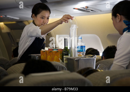 Female flight attendant serving water to girl on airplane Stock Photo