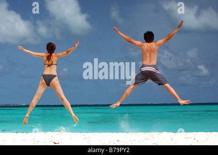 happy couple having fun on the beach jumping Stock Photo