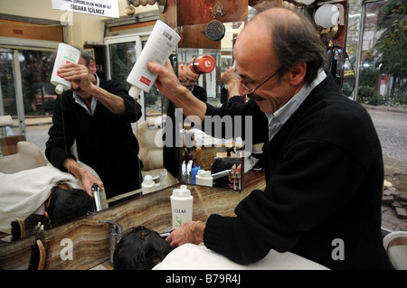 A traditional Turkish barber (Berber) giving a hair wash to an early morning client in his salon in Sultanahmet, Istanbul. Stock Photo