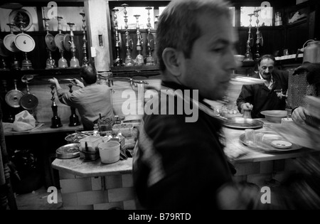 A local man delivers traditional water pipes (Shisha/Nargile) to customers in a bustling courtyard cafe in Istanbul, Turkey. Stock Photo