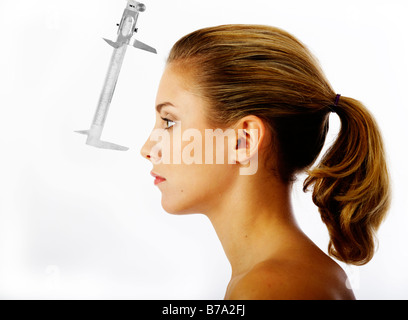 Young woman, distance between the forehead and the nose being measured with a caliper rule Stock Photo