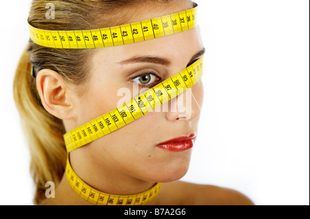 Young woman with measuring tape wrapped around her head and neck Stock Photo