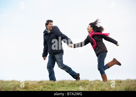 Couple Holding Hands And Running In The Park Stock Photo