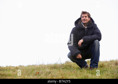Man Crouching In Park Stock Photo