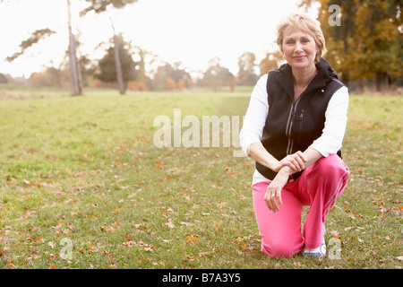 Portrait Of Senior Woman Crouching In The Park Stock Photo