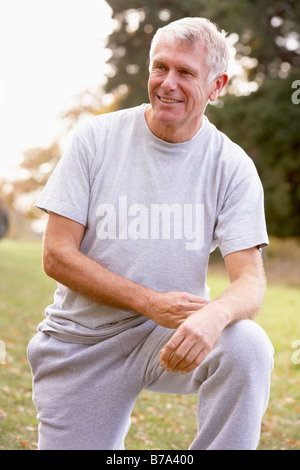 Portrait Of Senior Man Kneeling In Park Stock Photo