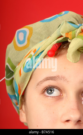 Teenage girl wearing hair curlers and head scarf looking dressed up to look like an old fashioned house wife Stock Photo