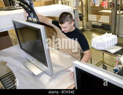 Employee packing a Loewe LCD television with flat panel display at Loewe AG factory in Kronbach, Bavaria, Germany Stock Photo