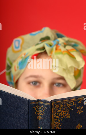 A book being read by a teenage girl wearing hair curlers and head scarf looking old fashioned Stock Photo