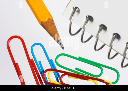 Colored paper clips, pencil and spiral notebook, detail Stock Photo