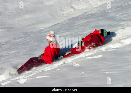 Two girls, 9 and 12 years old, riding on snow-sliders, Dolomites, Italy, Europe Stock Photo
