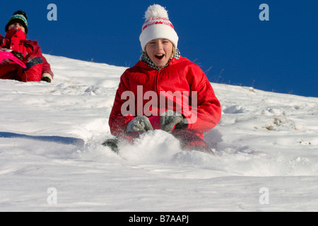 Two girls, 9 and 12 years old, riding on snow-sliders, Dolomites, Italy, Europe Stock Photo