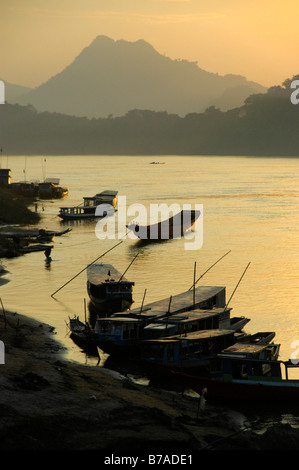 Sunset sky with boats on the shore of the Mekong River, Luang Prabang, Laos, South Asia Stock Photo