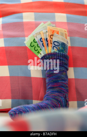 Savings stocking on a bed filled with euro notes, financial crisis anxiety Stock Photo