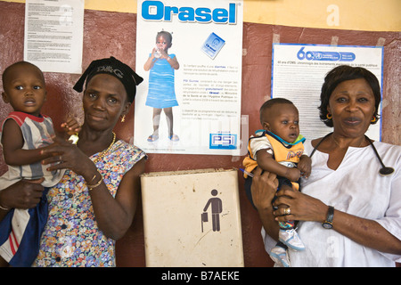 Children at a health center in Conakry, Guinea.  The poster on the wall advertises Orasel, oral rehydration salts (ORS). Stock Photo