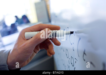 A man s hand writing mathematical equations on a whiteboard Stock Photo