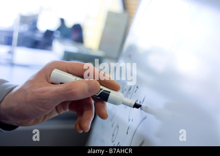 A man s hand writing mathematical equations on a whiteboard Stock Photo