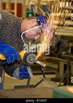 Student welder in metal shop using a grinder to smooth his creation All work depicted is accurate Stock Photo