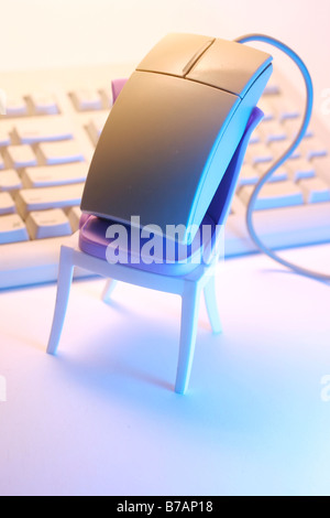 Computer mouse perched on a mini chair, keyboard