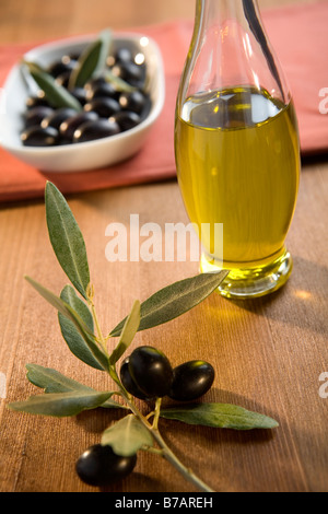 still life oil bottle black olives and olive branch on wooden table Stock Photo