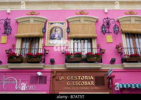 Brightly Coloured Facade of a Building with Balconies flower baskets and Window Blinds Almeria Spain Stock Photo