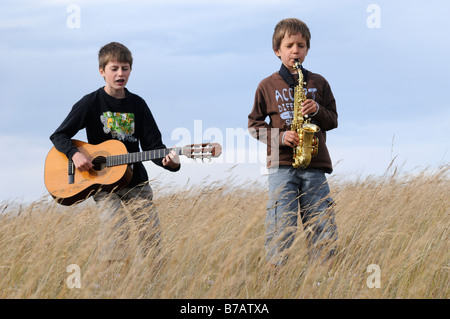 Boys Playing Music in Field Stock Photo