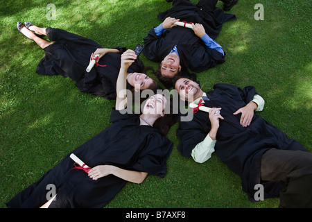 College Graduates Lying on Ground Taking Pictures With Camera Phone Stock Photo