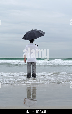 Man Holding Umbrella on Beach Stock Photo