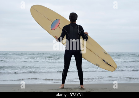 Man Holding Surfboard on Beach Stock Photo