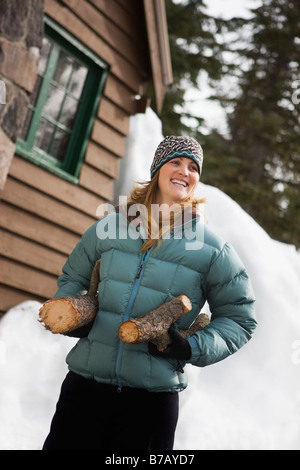 Woman Carrying Logs by Cabin, Government Camp, Oregon, USA Stock Photo