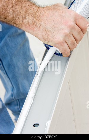 Closeup of a man s hands using a caulking gun on aluminum Stock Photo